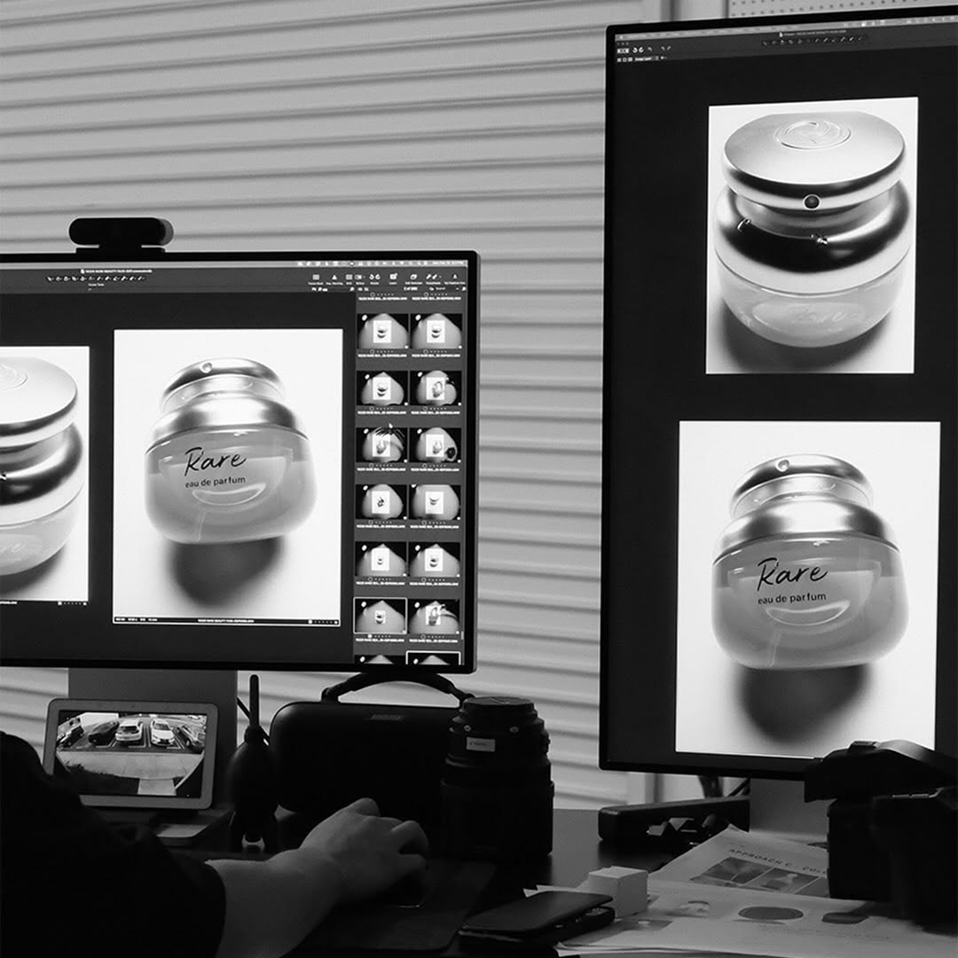 Editing product photos of “Rare” perfume on dual monitors in a photography studio.