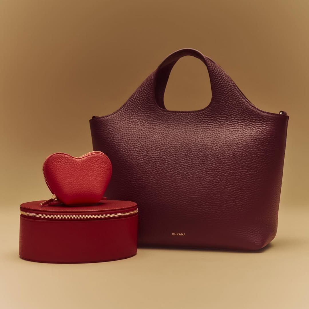 Burgundy leather tote bag with red heart prop on beige backdrop